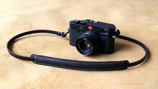 Analog film camera with leather strap on wooden table
