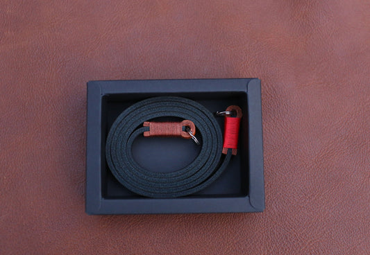 Film camera with handmade leather strap resting beside a cup of coffee in morning café