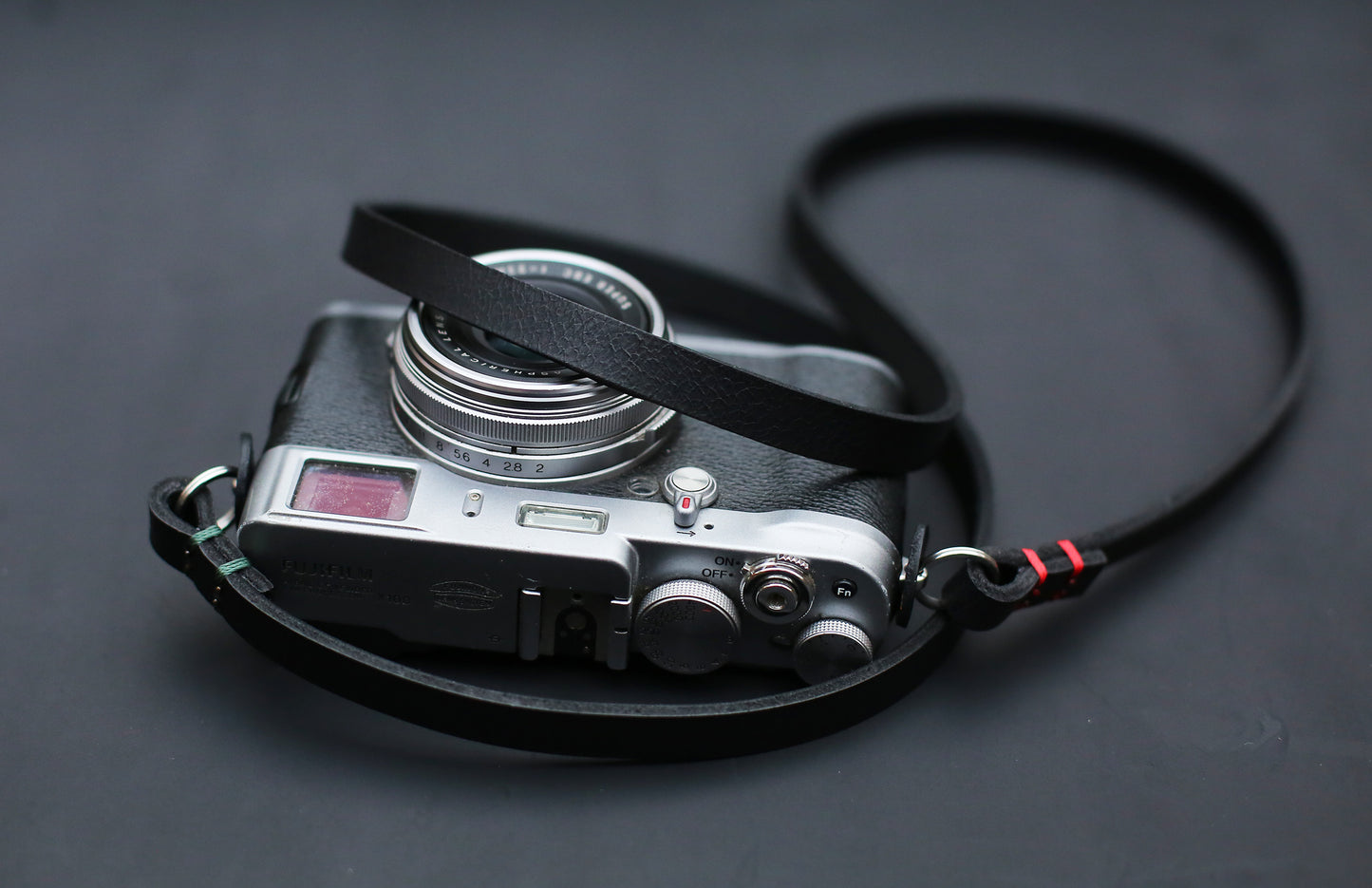 Black buffalo leather camera strap close-up, showing waxed thread detail