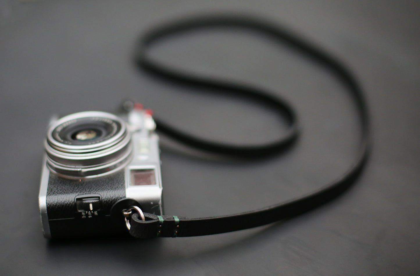 Slim 10mm black leather camera strap with protective round pads and metal split rings