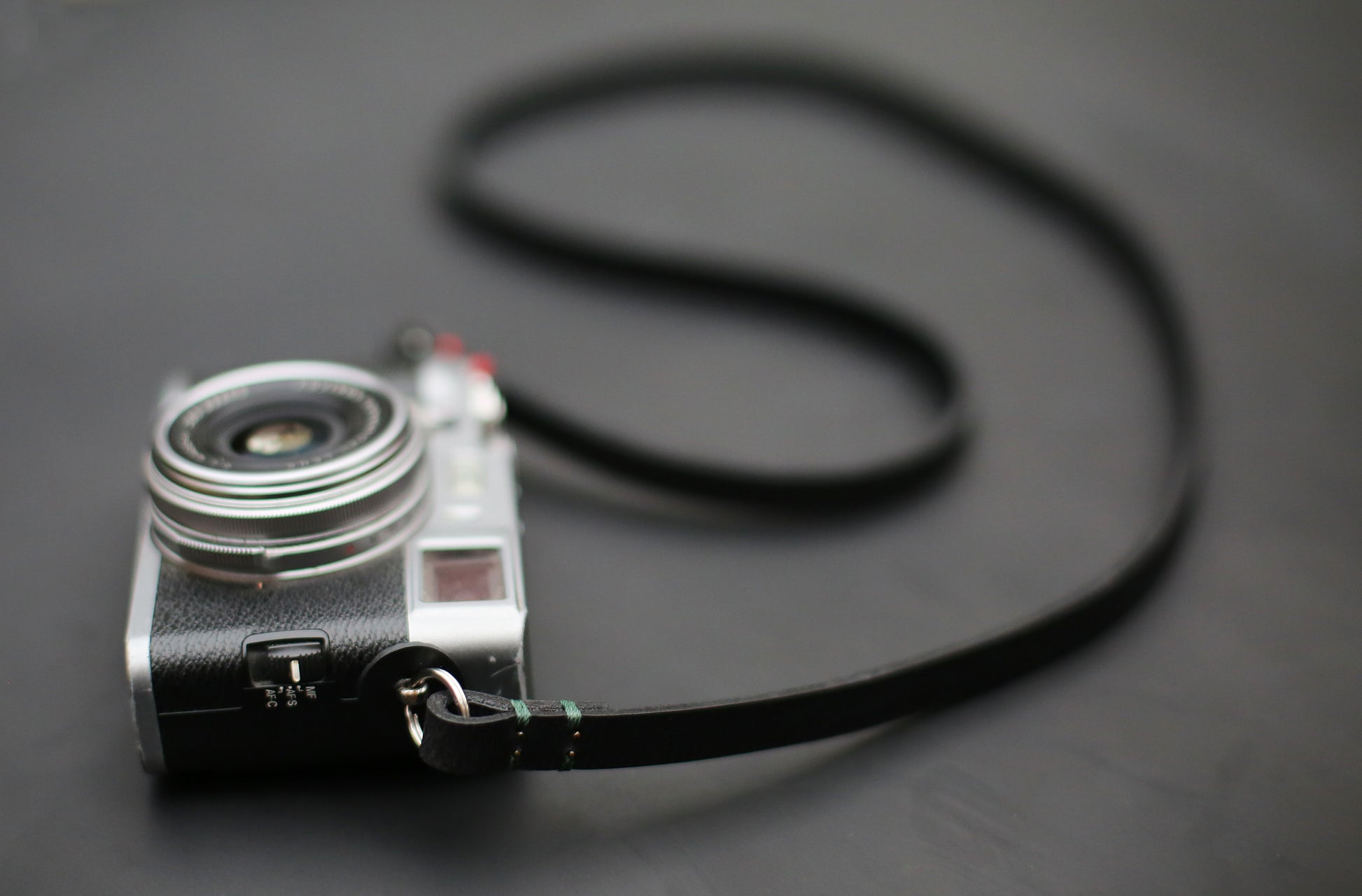 Slim 10mm black leather camera strap with protective round pads and metal split rings