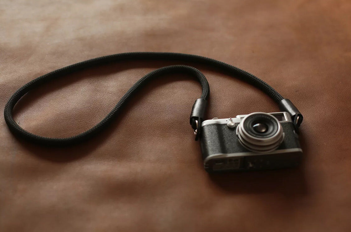 black rope camera strap on leather surfacewindmup