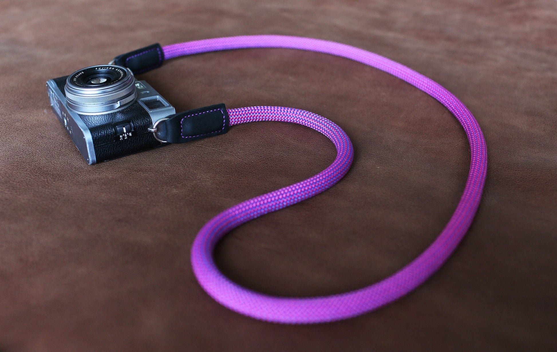 Close-up of purple camera strap on brown leather surface