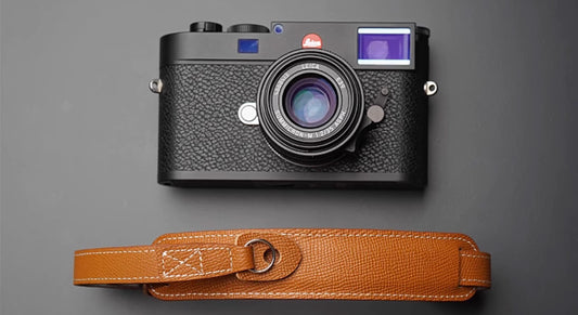 Handmade brown leather camera strap on wooden table