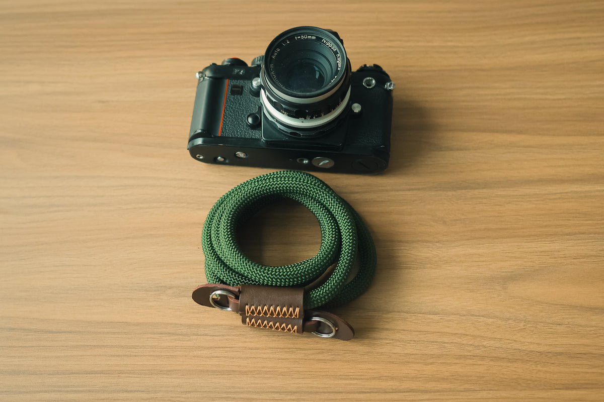 Army green rope camera strap attached to a film camera