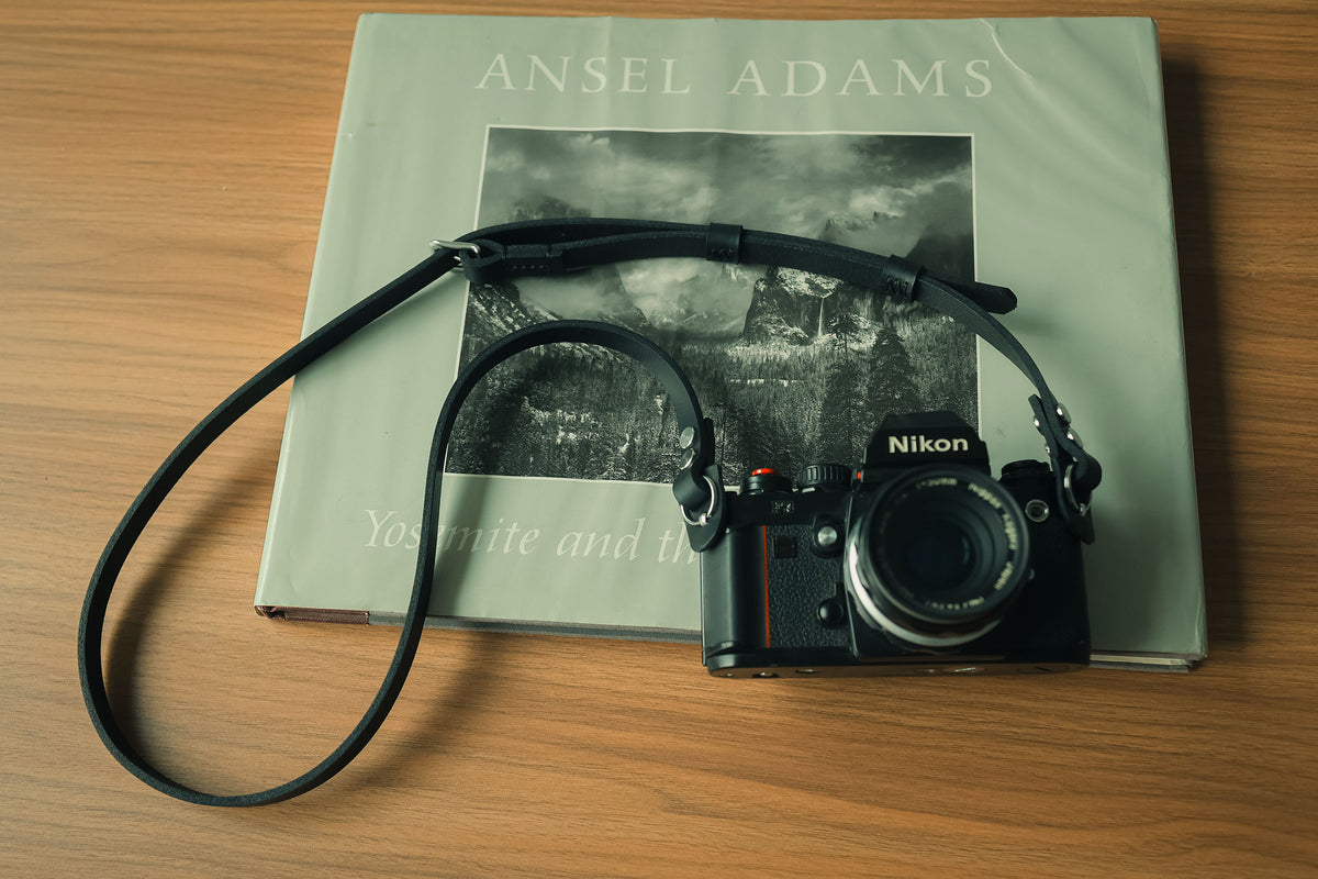 Black camera strap arranged with a vintage film camera