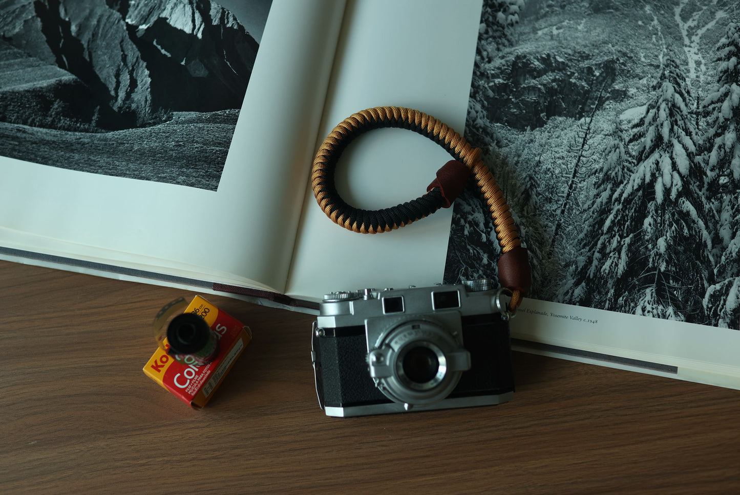 Top view of black and gold braided paracord camera wrist strap with brown leather ends