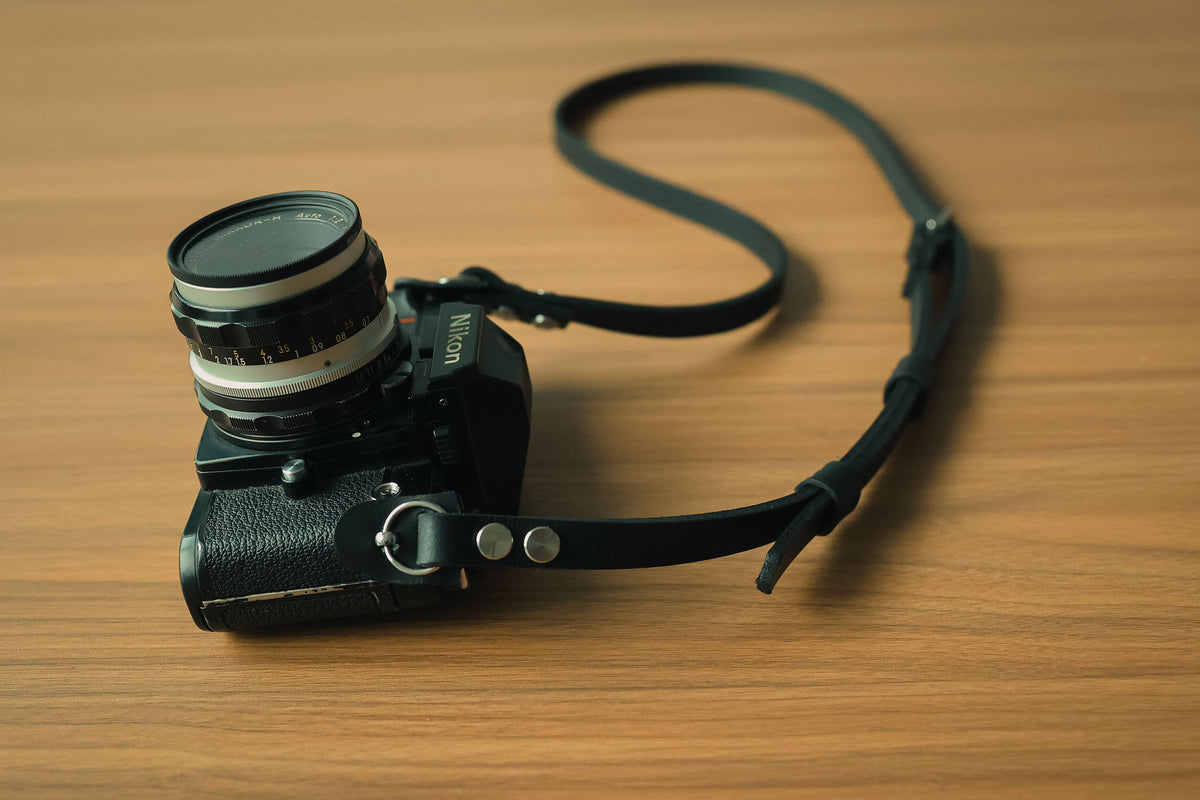 Close-up of black leather camera strap attached to camera lugs