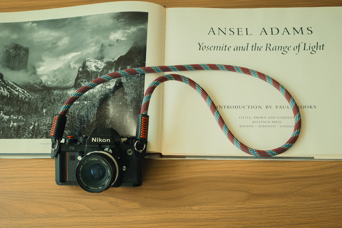 Black full-grain leather camera strap end with red stitching