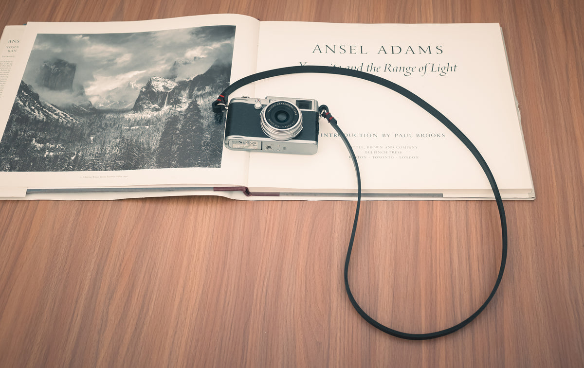 Handmade black leather strap attached to a mirrorless camera