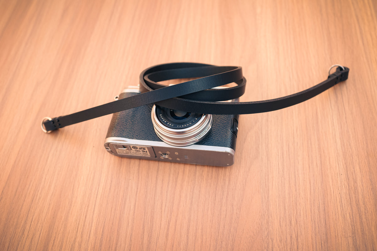 Black buffalo leather camera strap styled with a vintage camera