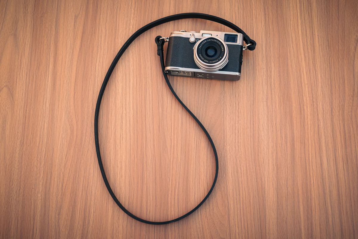 Black leather camera strap with contrasting red waxed-thread stitching