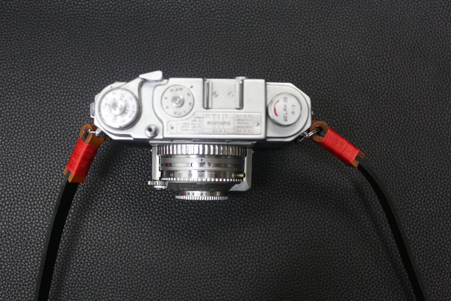Stylish handmade black camera strap with red accent for photographers.