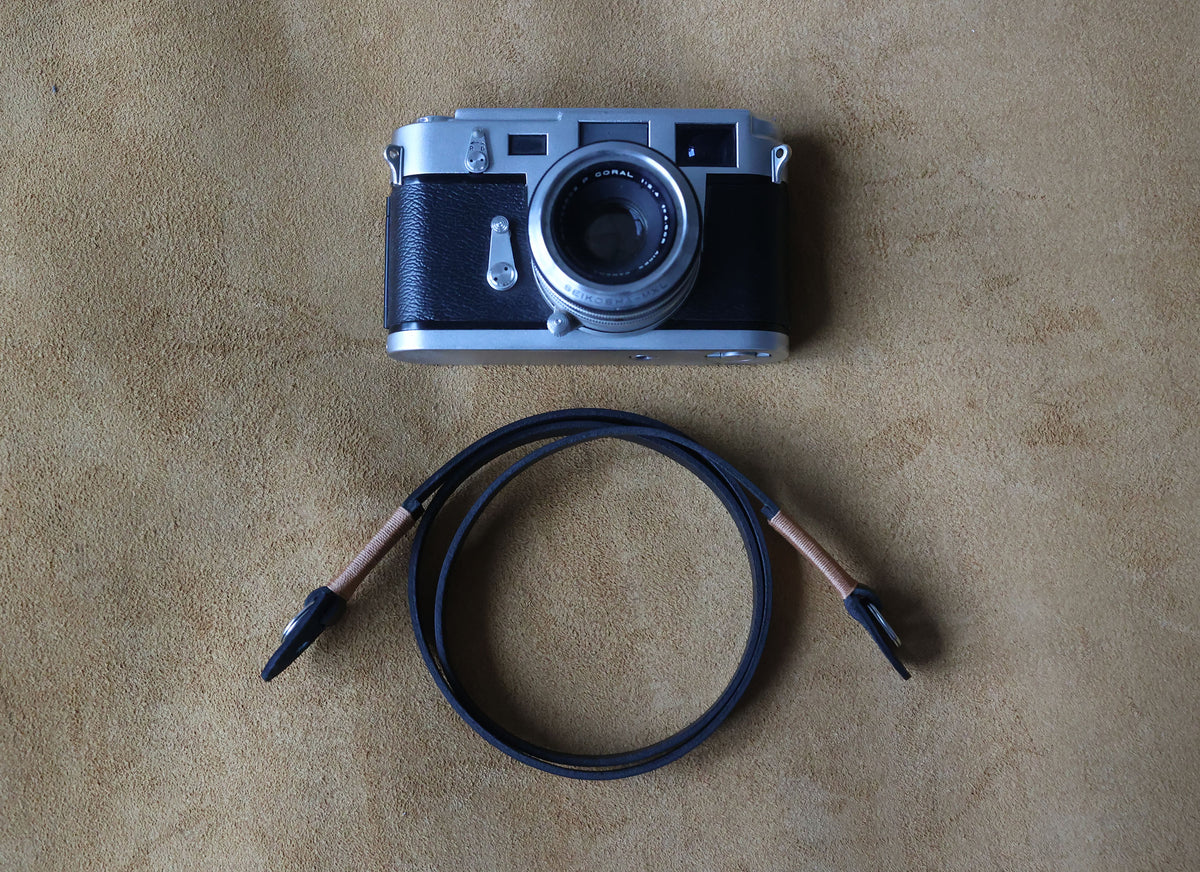 Close-up of a soft black nubuck leather camera strap with tan thread accents