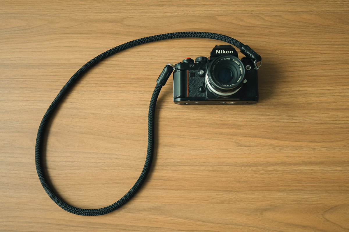 Hand stitching with black waxed thread on a leather camera strap