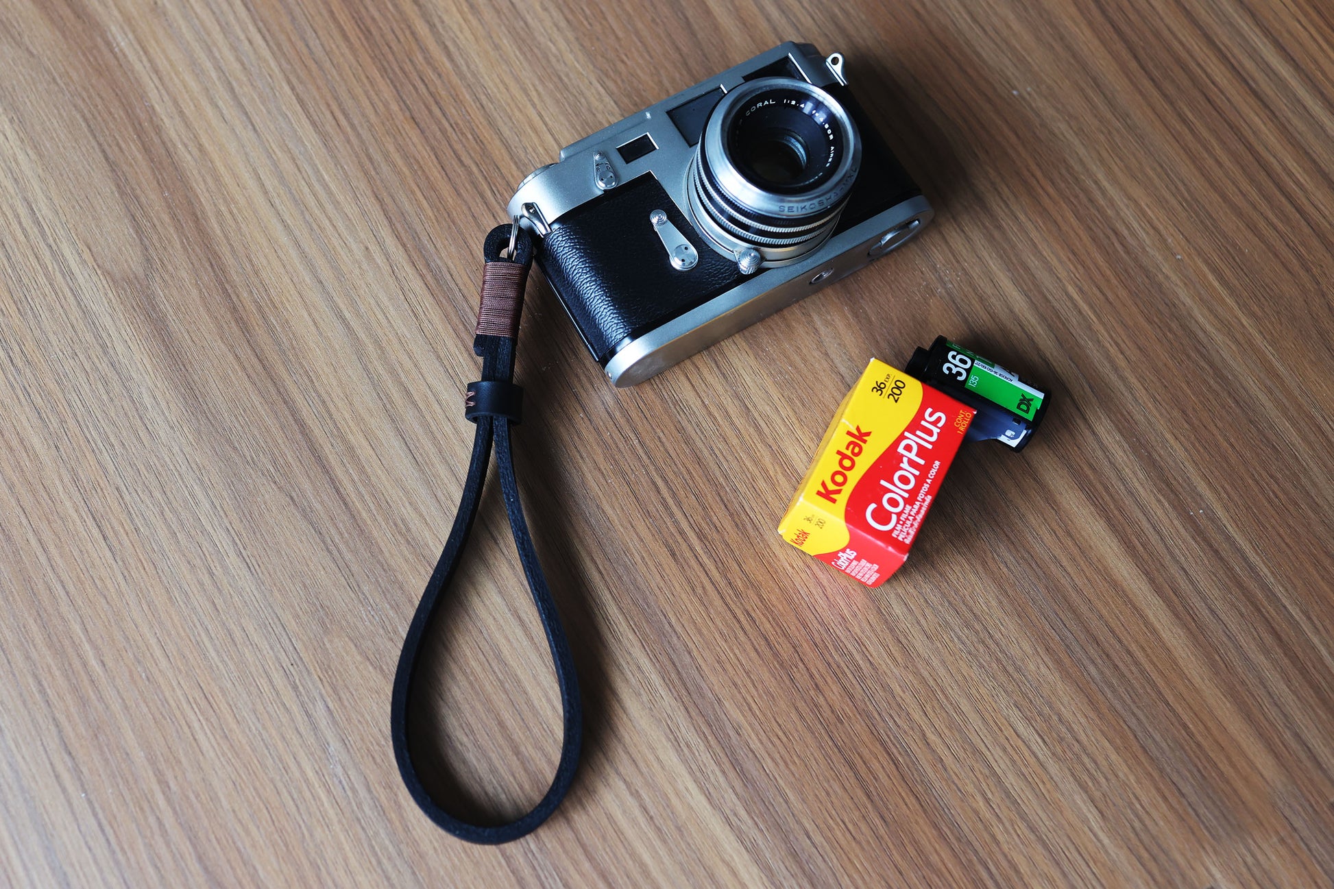 Coffee brown leather camera wrist strap with hand-wrapped thread attached to a compact camera