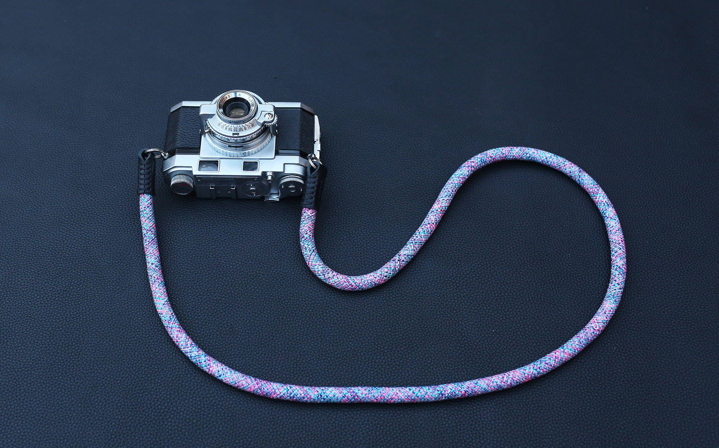 Violet elastic camera strap lifestyle flat lay on dark background