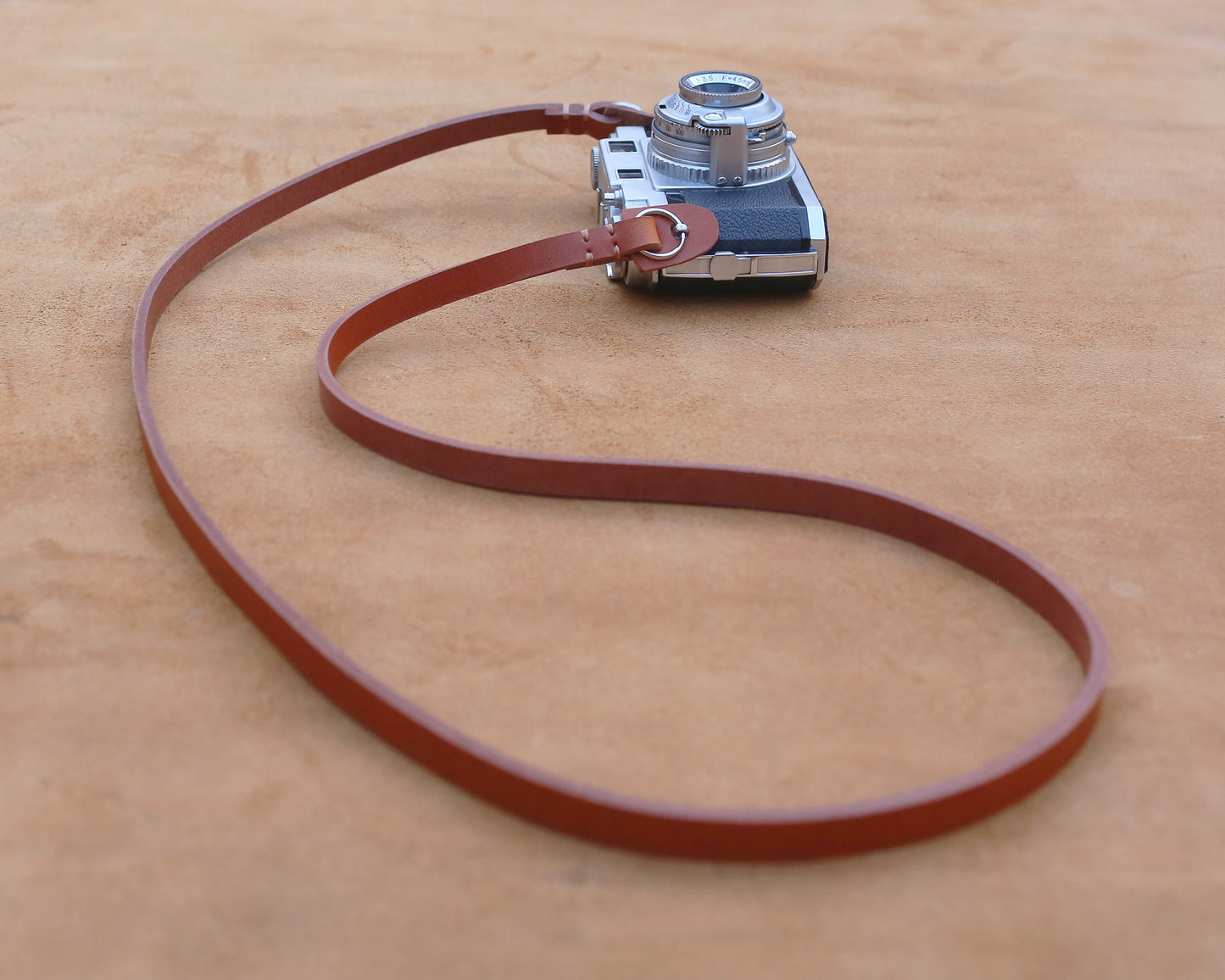 Premium full-grain tan leather camera sling with secure metal ring attachment