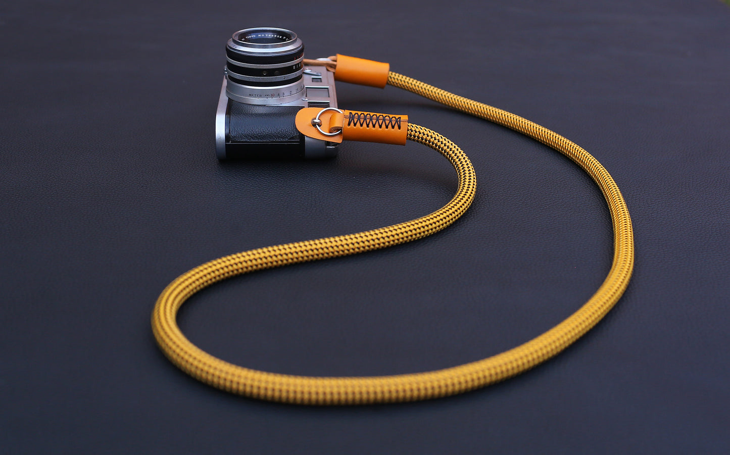  Flat lay of gold climbing rope camera strap on dark background