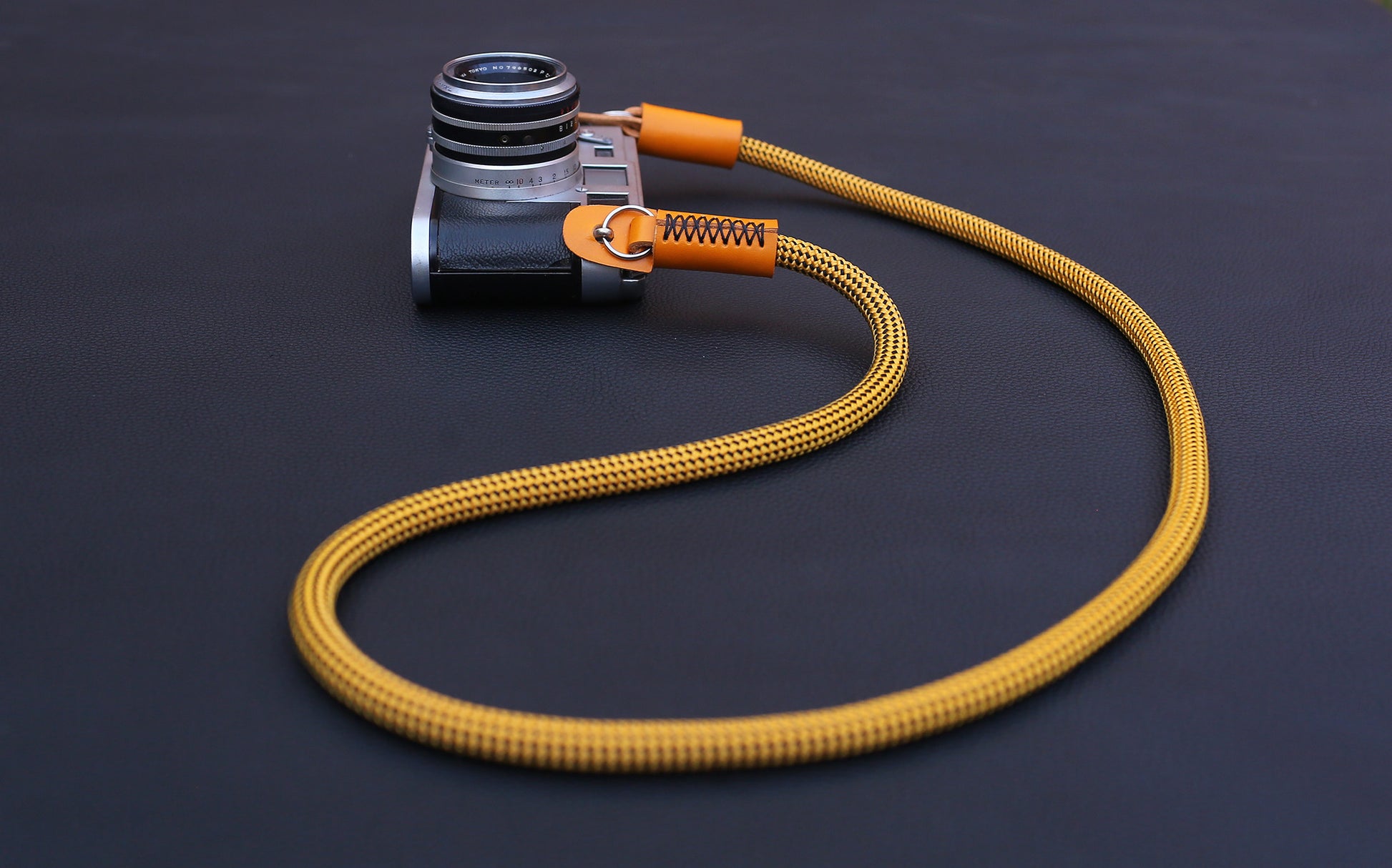  Flat lay of gold climbing rope camera strap on dark background