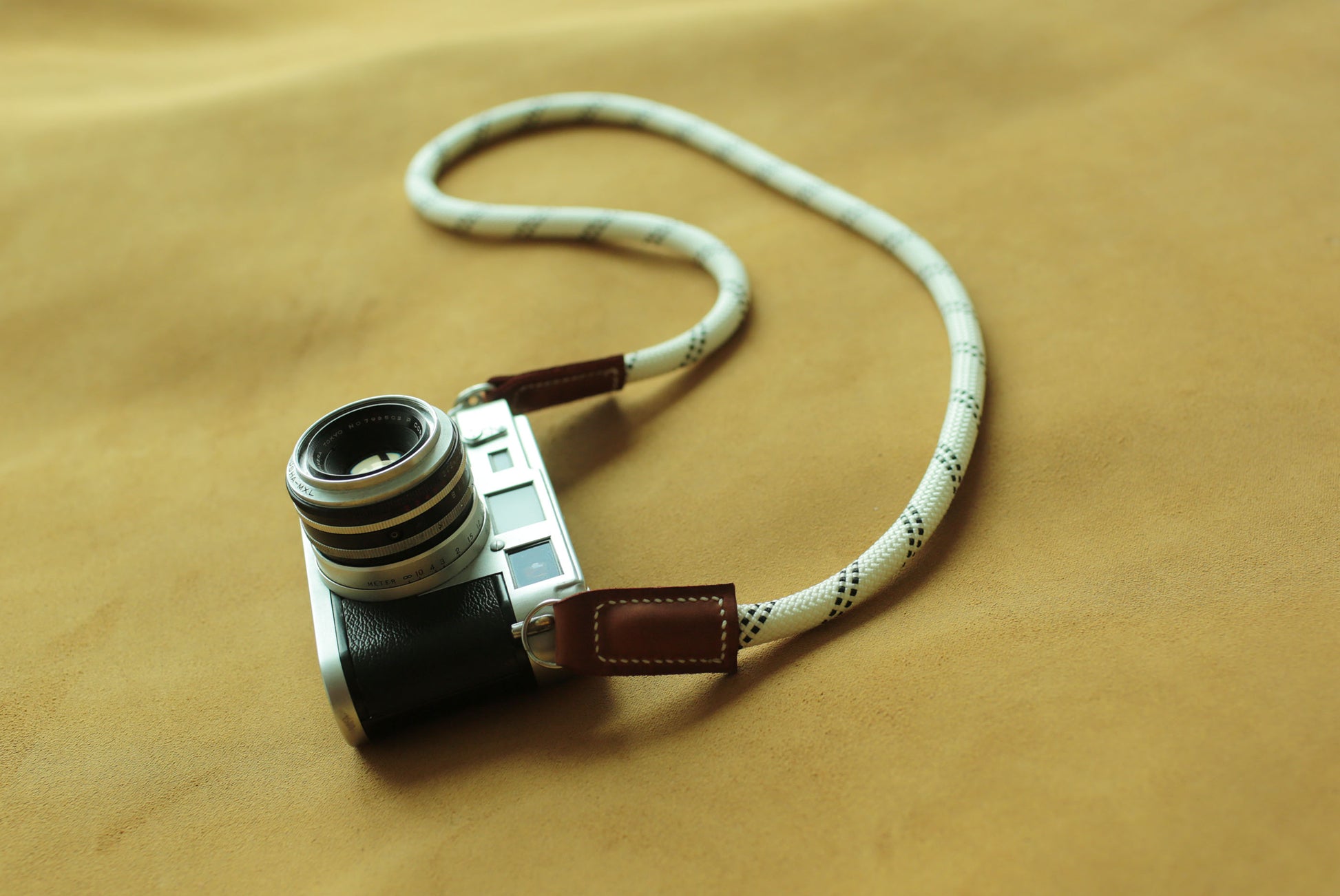Hand-stitched brown leather ends on a white climbing rope strap