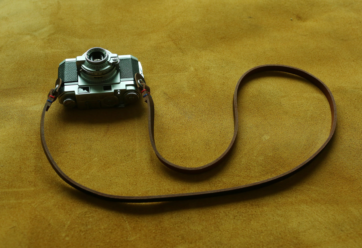 Detailed view of hand-stitched leather strap with colorful wax thread