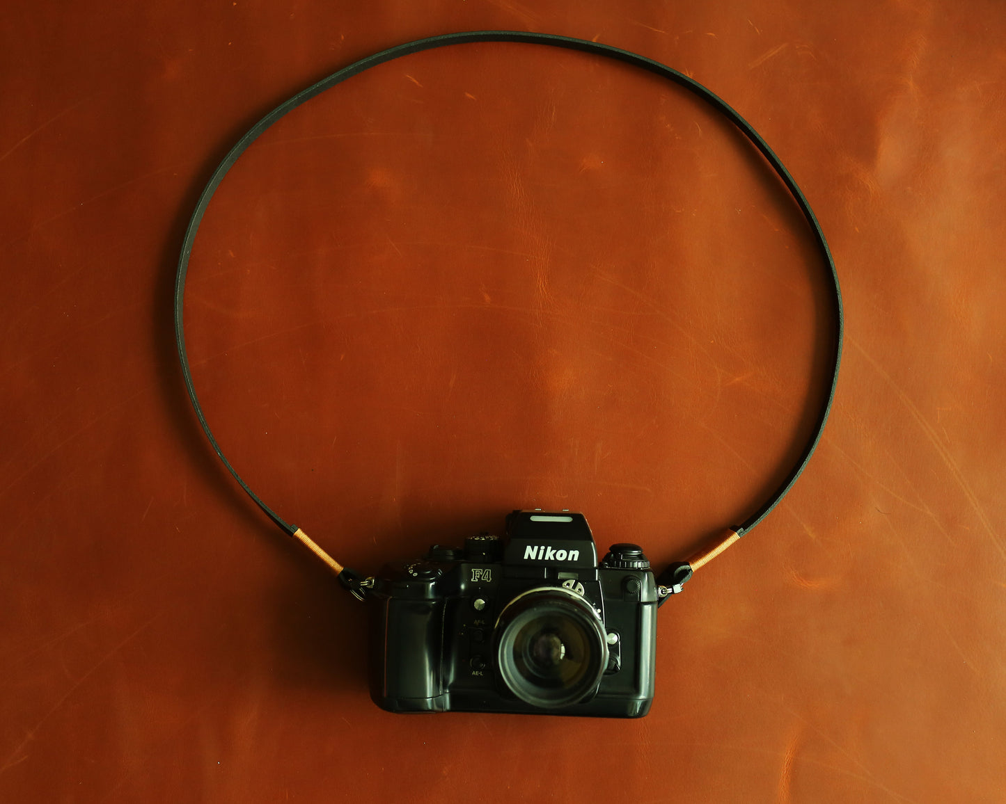 Handmade black leather camera strap paired with a vintage Nikon F4 film camera.
