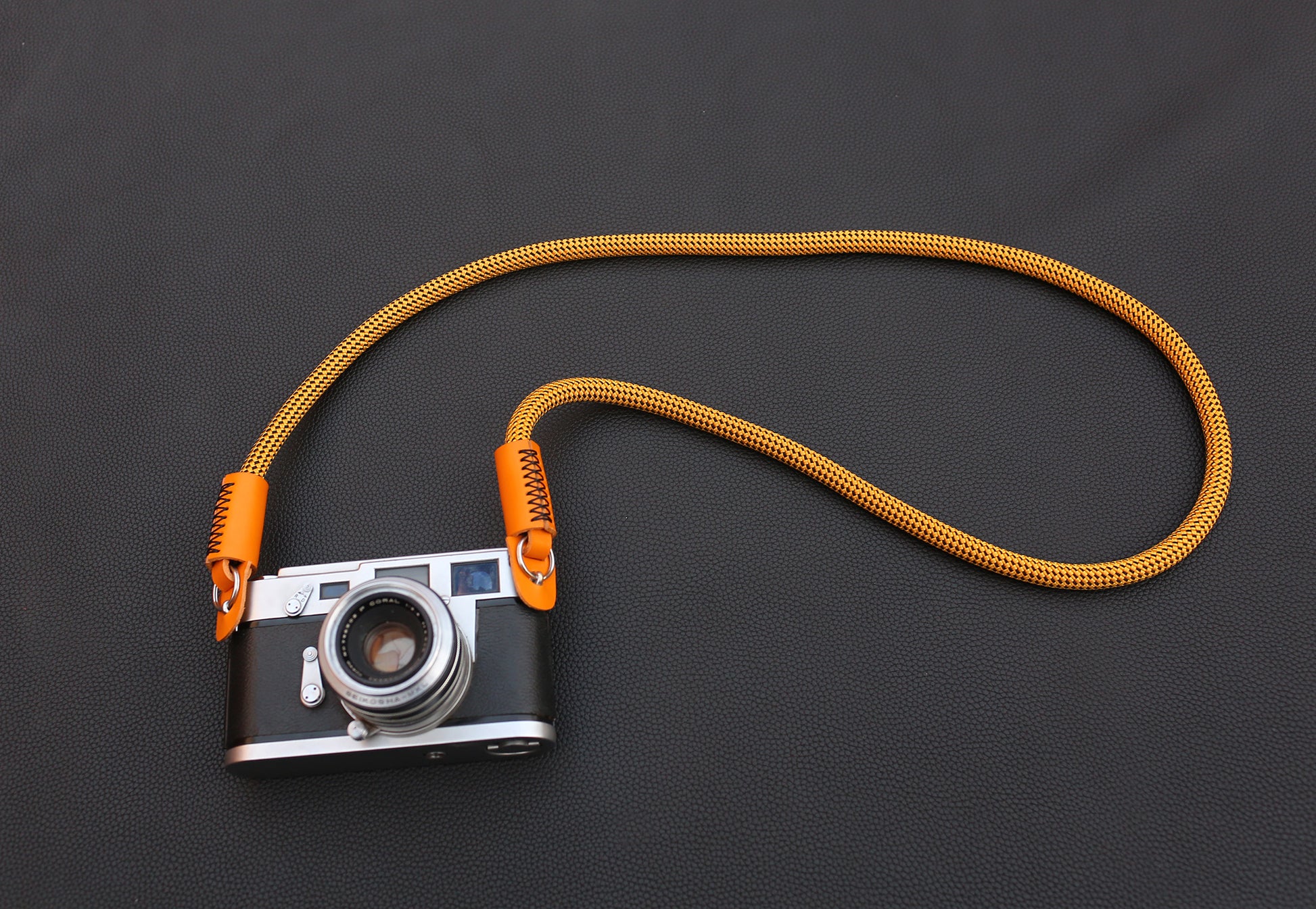 Handmade gold camera strap featuring orange grain leather cap