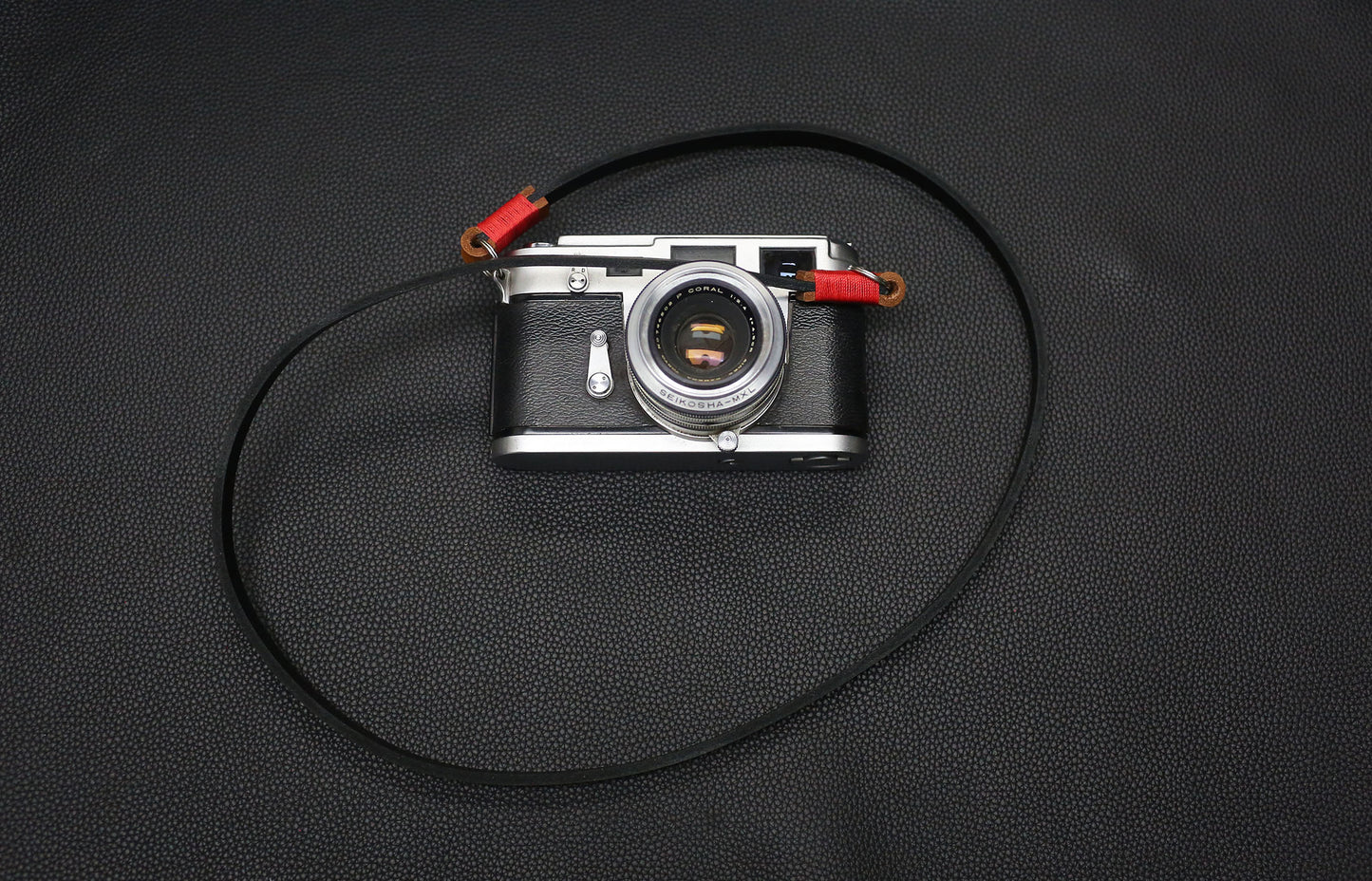 Close-up of red waxed thread binding on handmade leather strap.