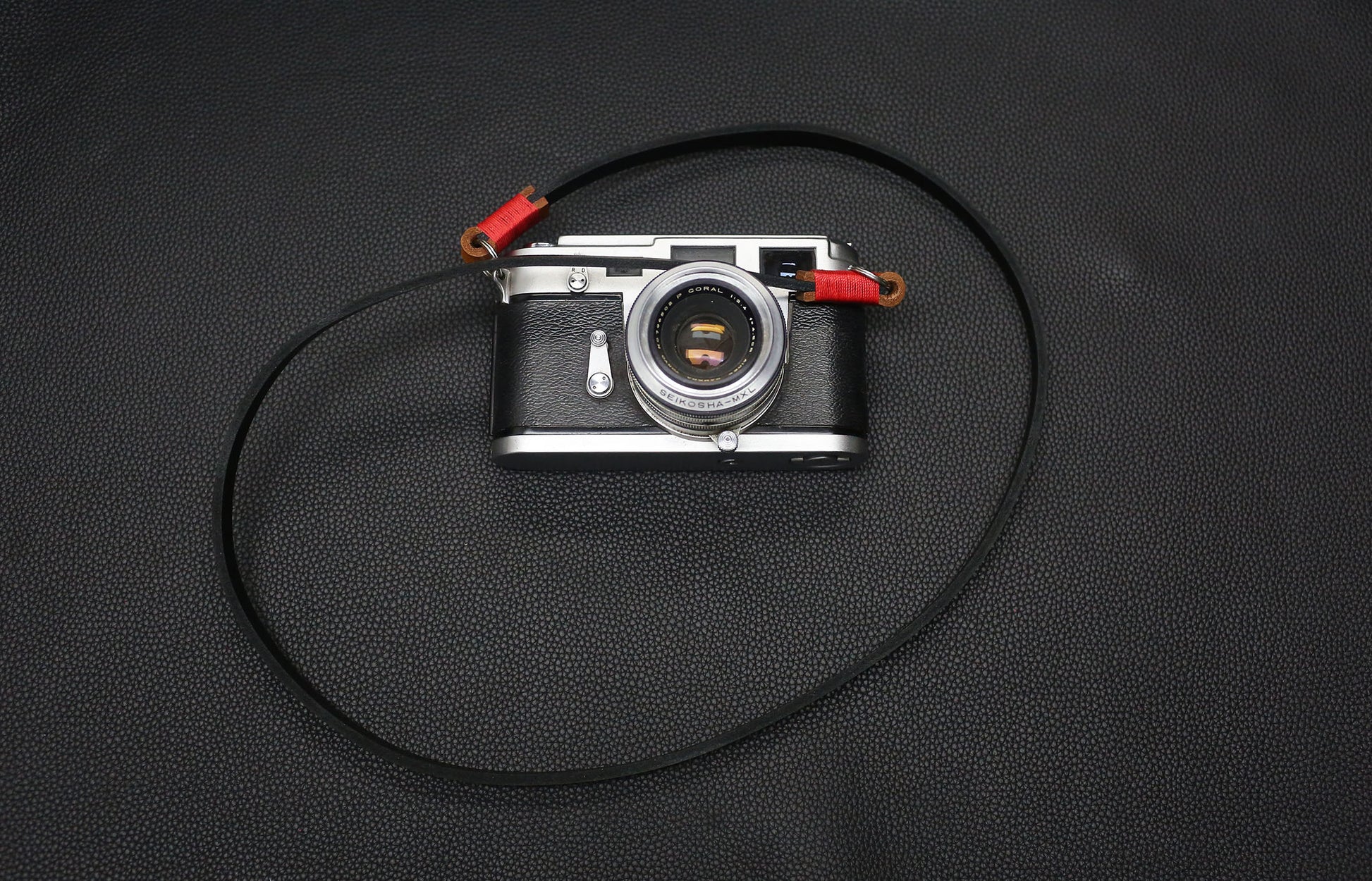 Close-up of red waxed thread binding on handmade leather strap.