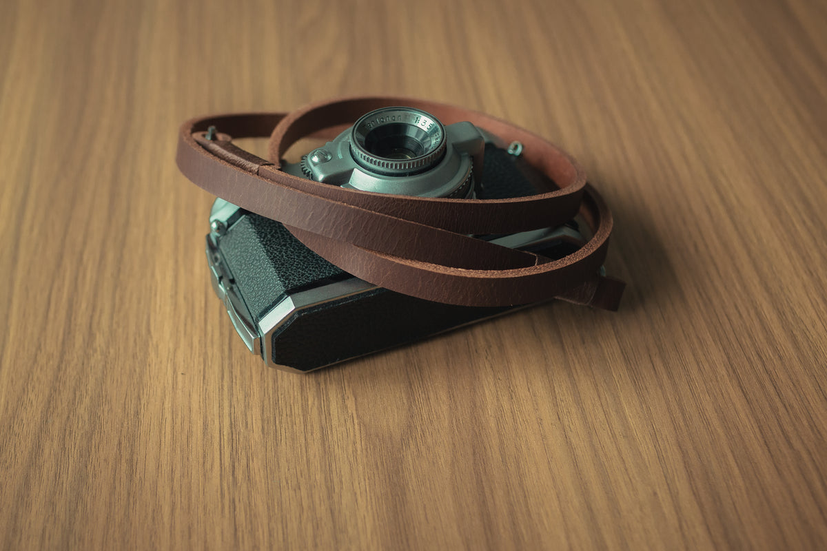 Metal split ring attachment detail on tan leather camera strap