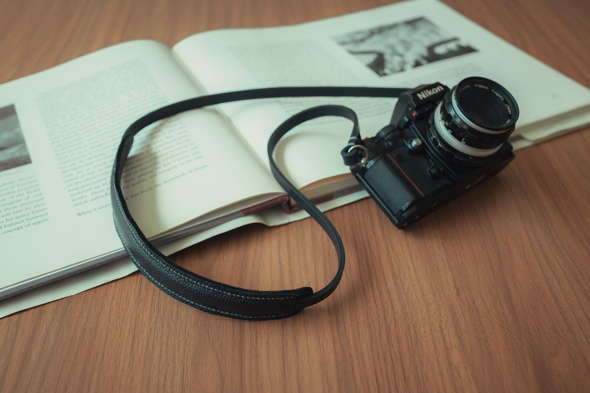 Minimalist black leather camera strap attached to a vintage film camera