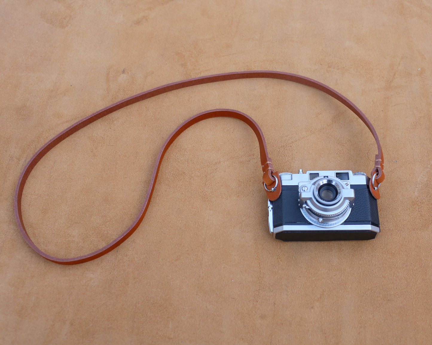 Minimalist slim leather neck strap attached to a classic rangefinder camera