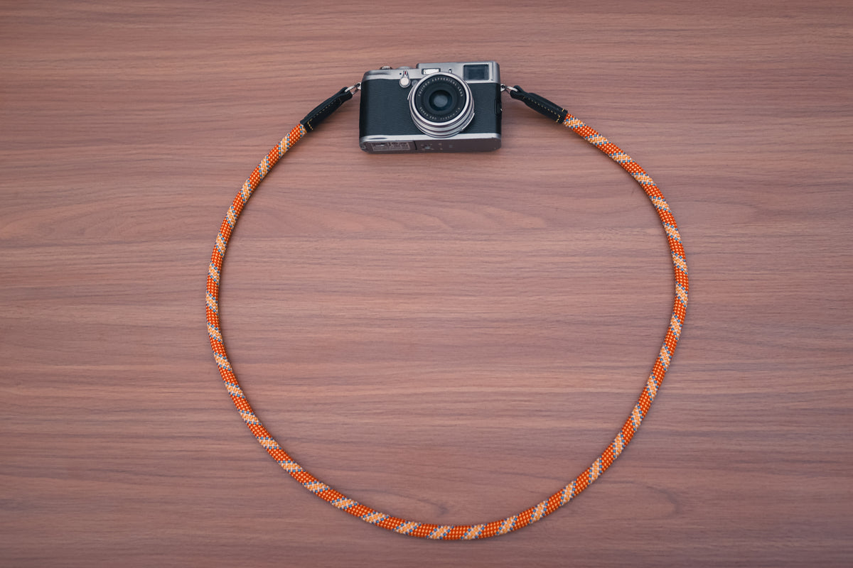 Orange and gold patterned climbing rope camera strap with black leather ends