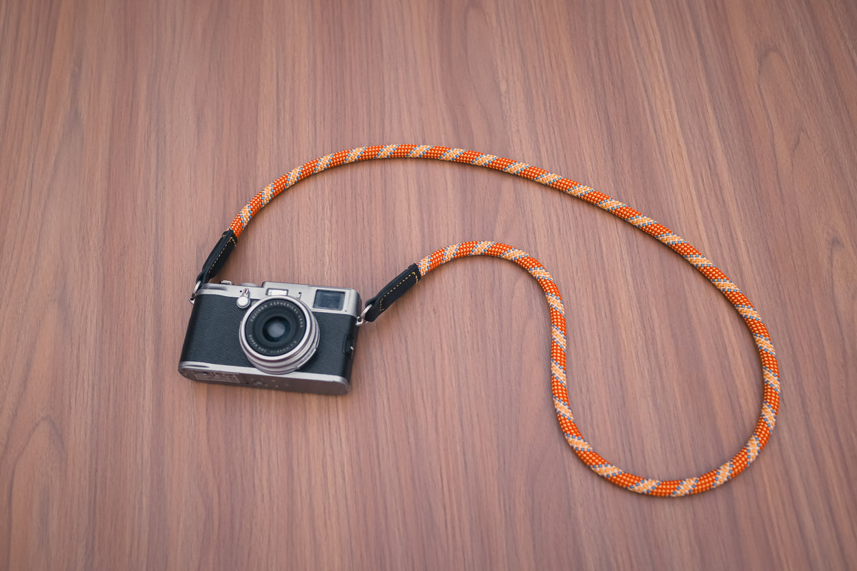Orange patterned camera strap with black vegetable-tanned leather ends