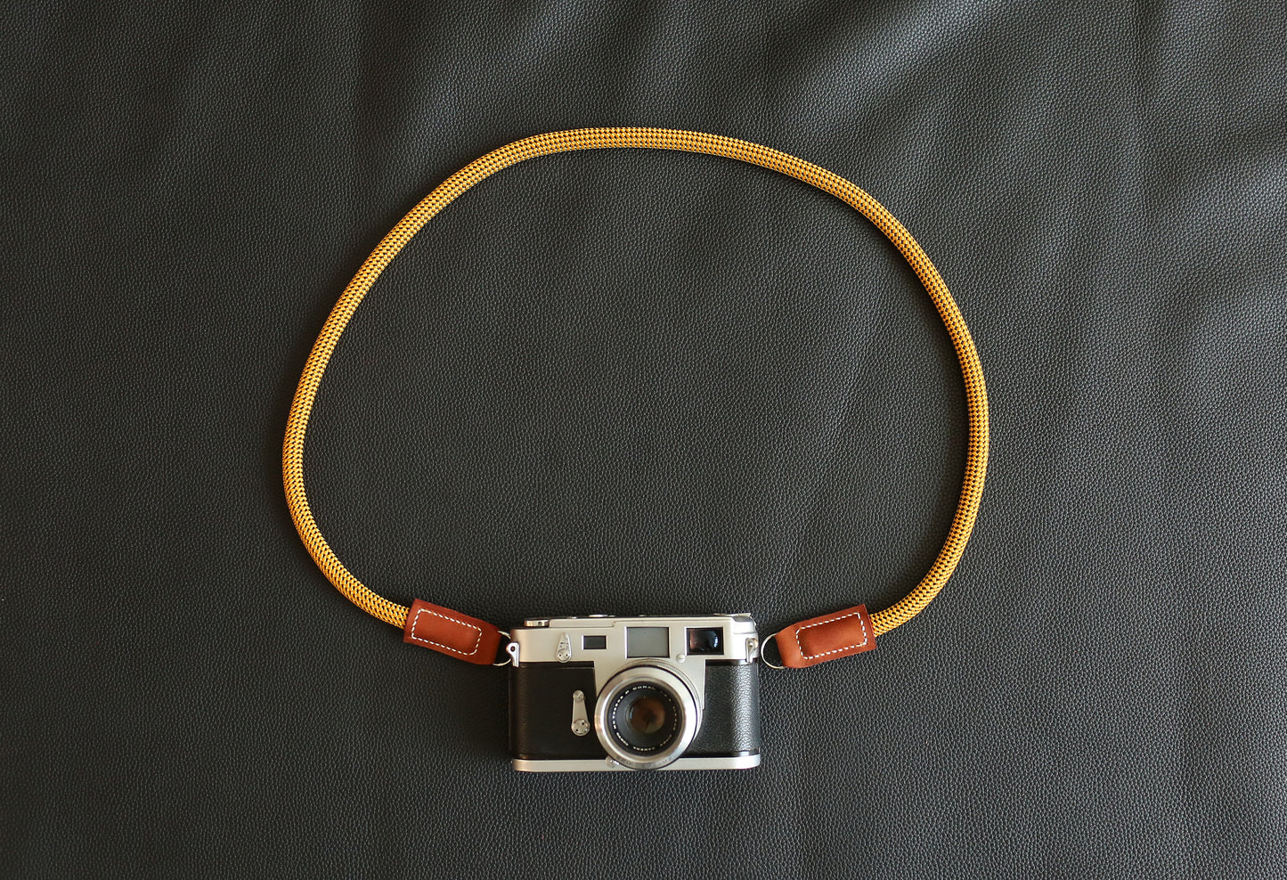 The Radiant Explorer Gold camera strap mounted on a vintage rangefinder camera