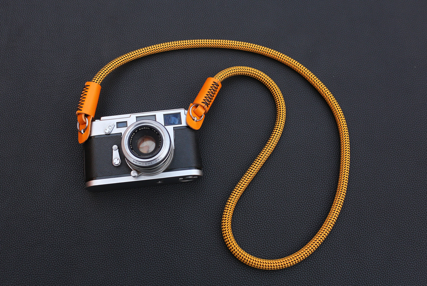 Hand stitching detail on orange leather camera strap end