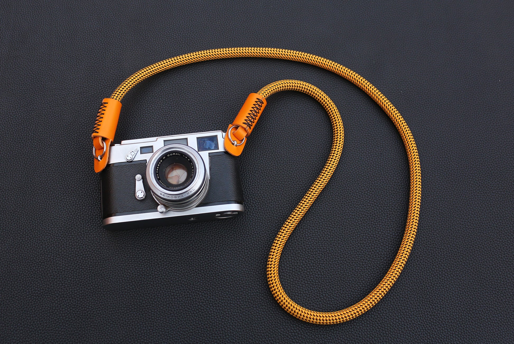 Hand stitching detail on orange leather camera strap end