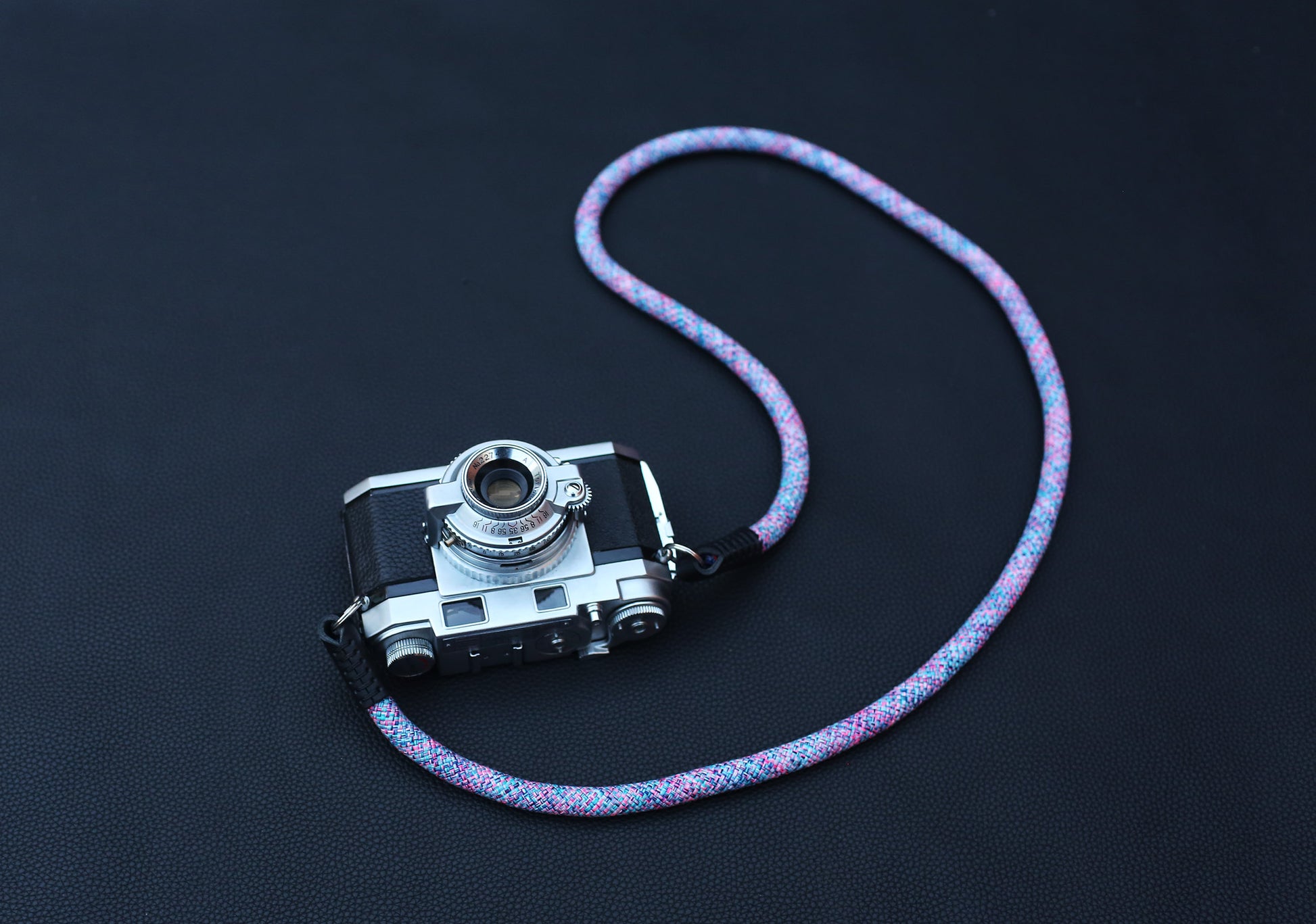 Metal ring attachment detail on violet elastic camera strap