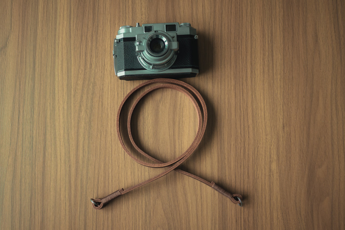 Close-up detail of handmade tan leather camera strap and stitching