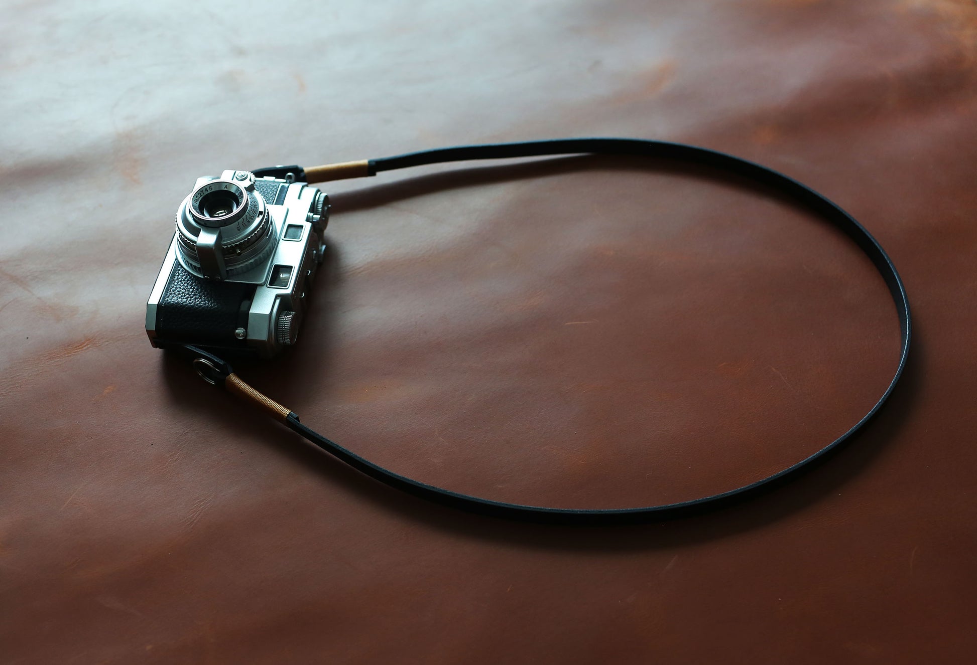 Vintage style black leather camera neck strap with tan wax thread accent, compatible with Leica and Fujifilm