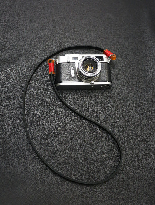 Handmade black leather camera strap with red waxed thread by Windmup.