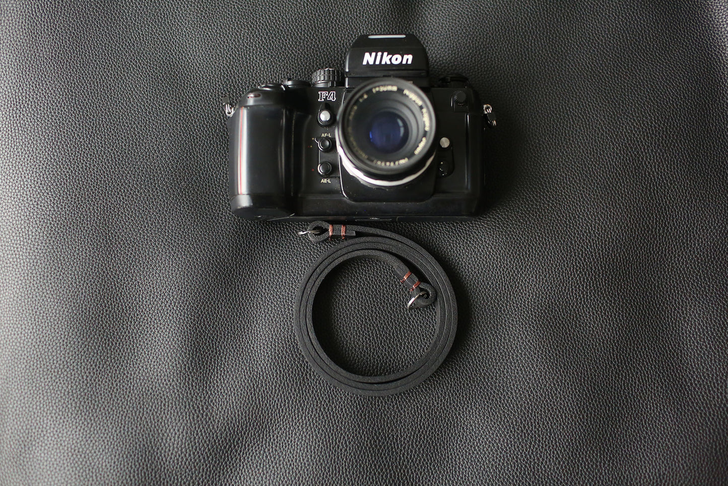 Handmade black leather camera strap on wooden table