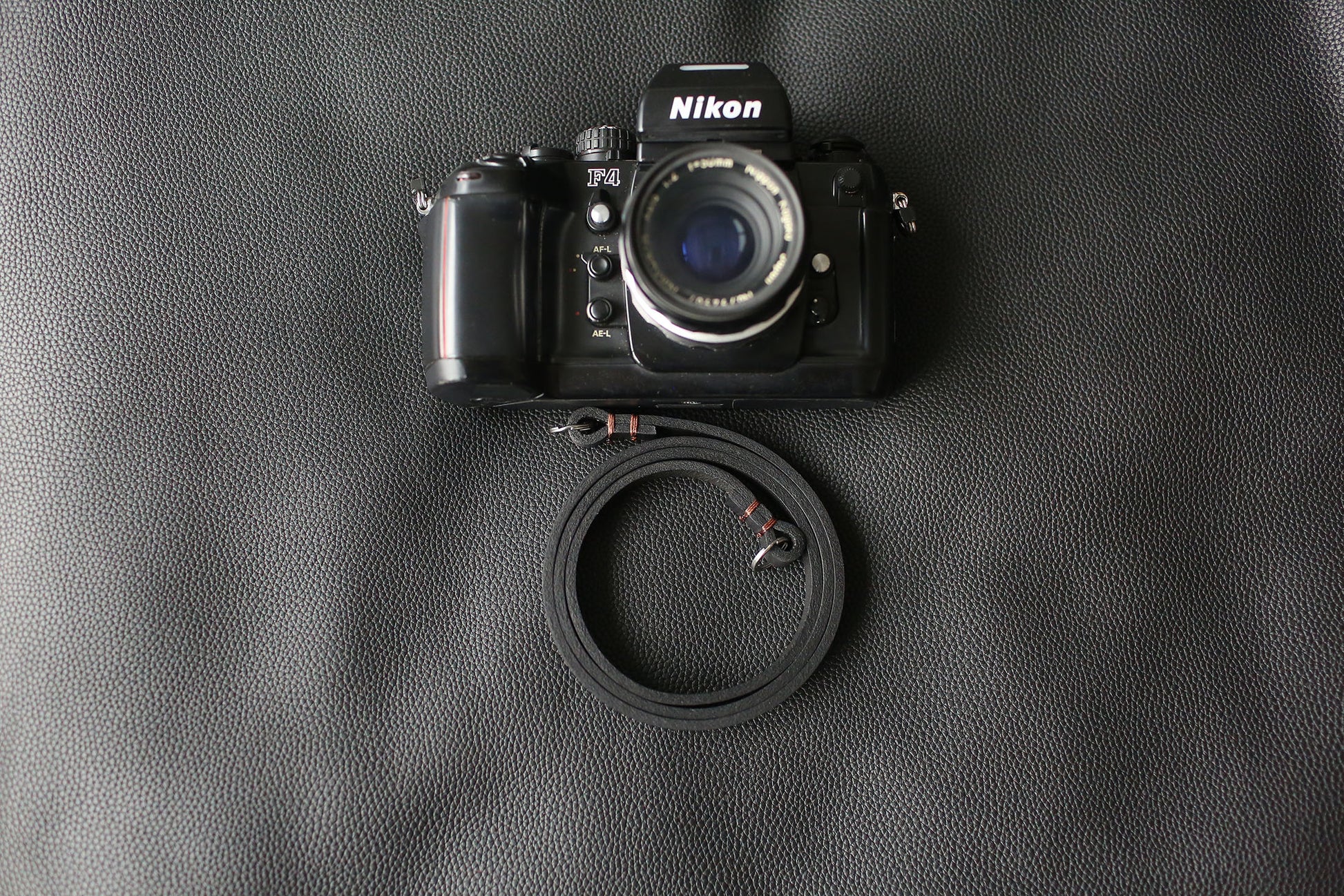Handmade black leather camera strap on wooden table