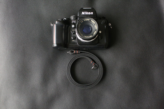 Handmade black leather camera strap on wooden table