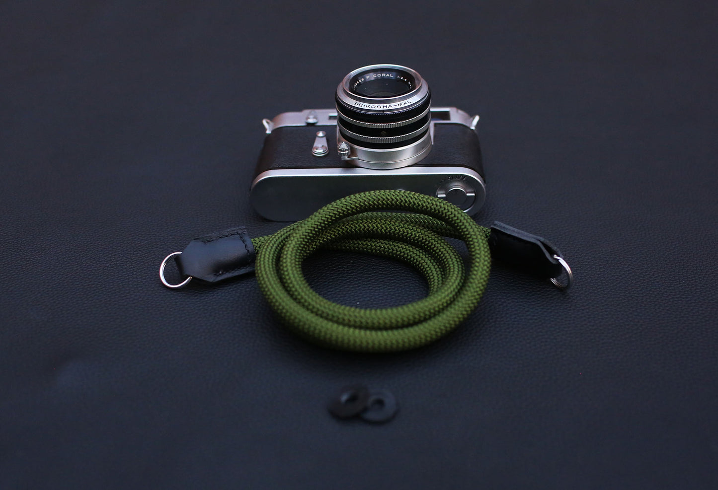  army green rope camera strap laid flat on wooden tabletop