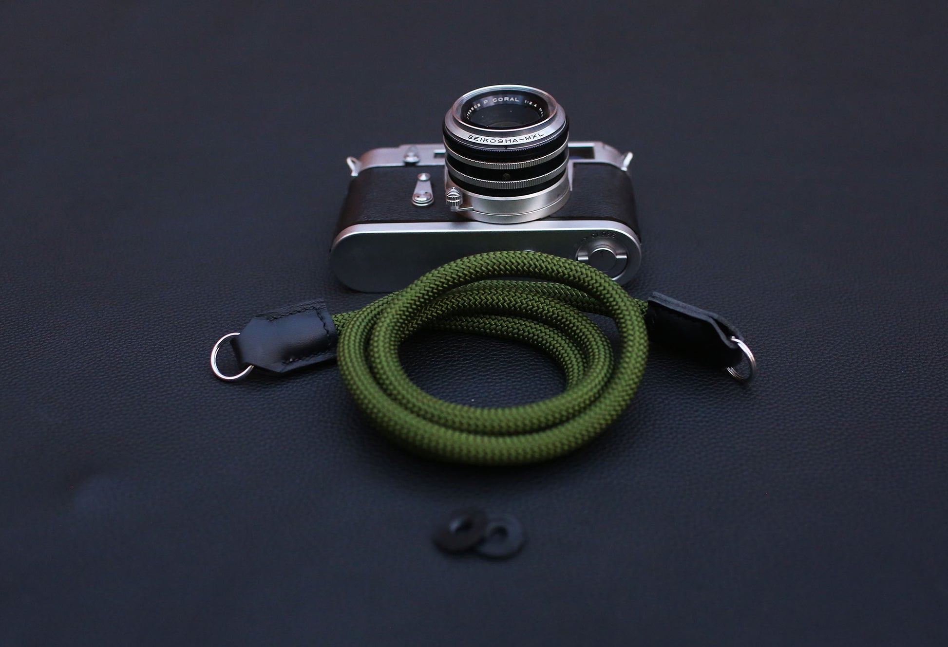  army green rope camera strap laid flat on wooden tabletop