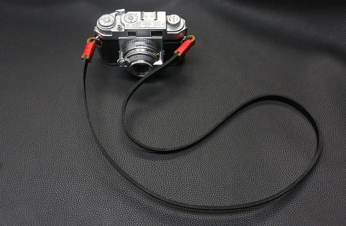 Stylish handmade black camera strap with red accent for photographers.