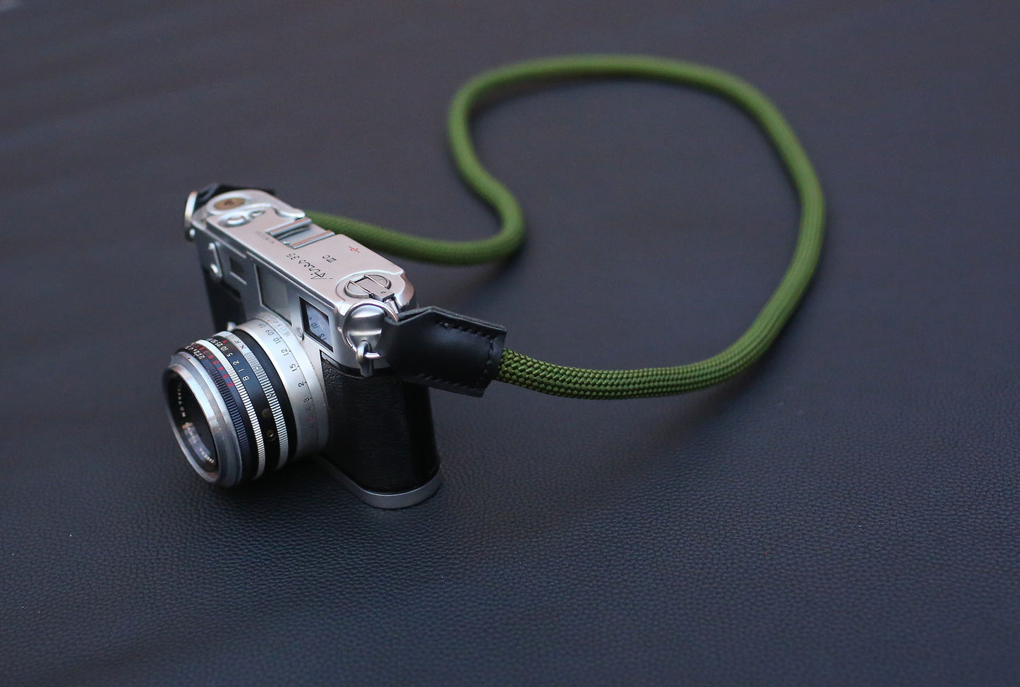 camera with army green rope strap laid in smooth curve