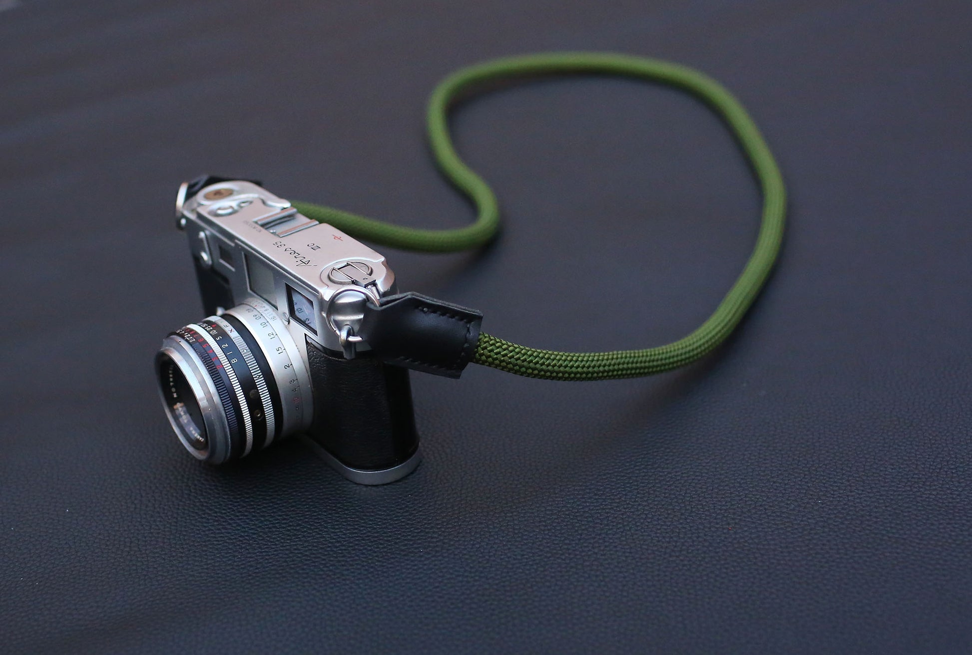 camera with army green rope strap laid in smooth curve